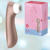 A rose gold Satisfyer Pro 2+, complete with a white tip, is displayed beside its packaging box labeled "Satisfyer Pro 2+ Air Pulse Stimulator + Vibration," featuring a minimalist illustration of a woman. The softly blurred background with bokeh lights enhances the product's elegant presentation.